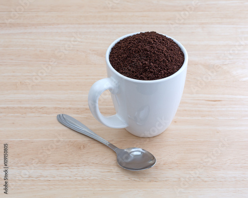 Kona coffee ground beans in a cup with spoon