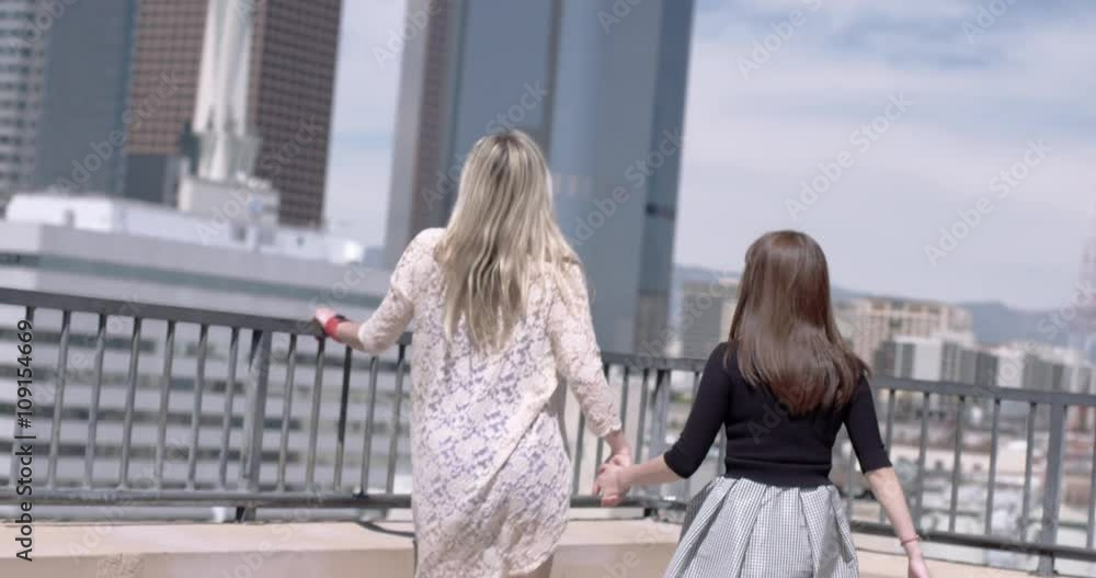 Stockvideon Two attractive young women walk holding hands to look at a ...