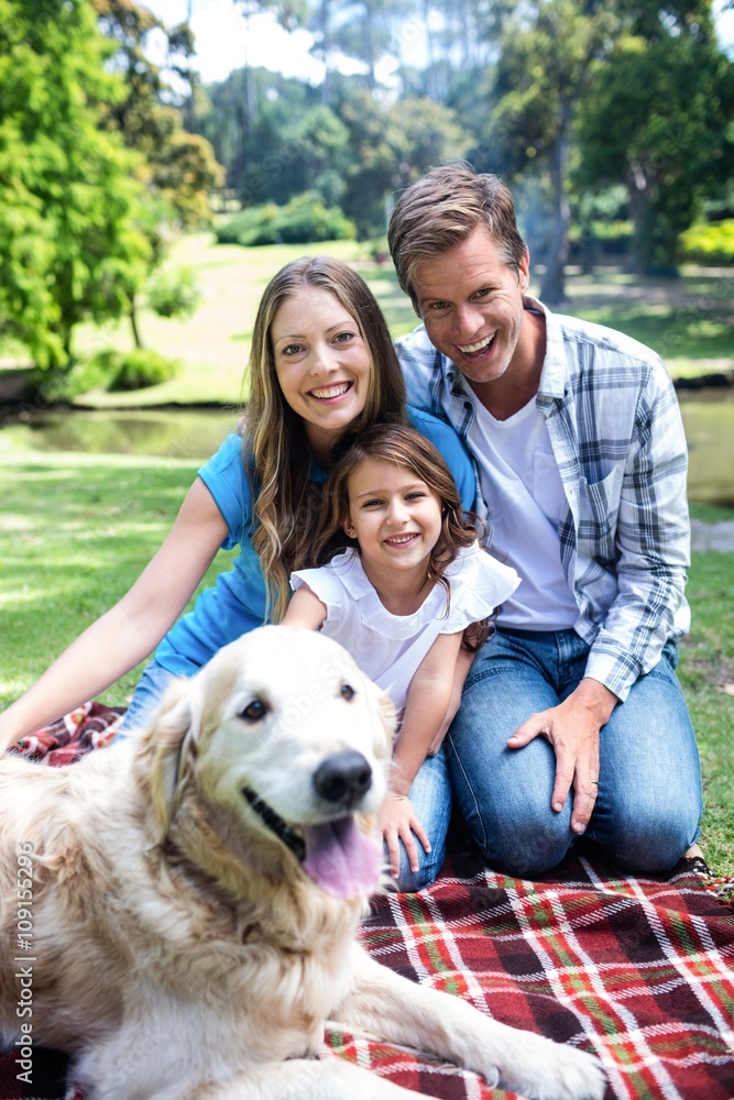 Happy family sitting in the park with their dog