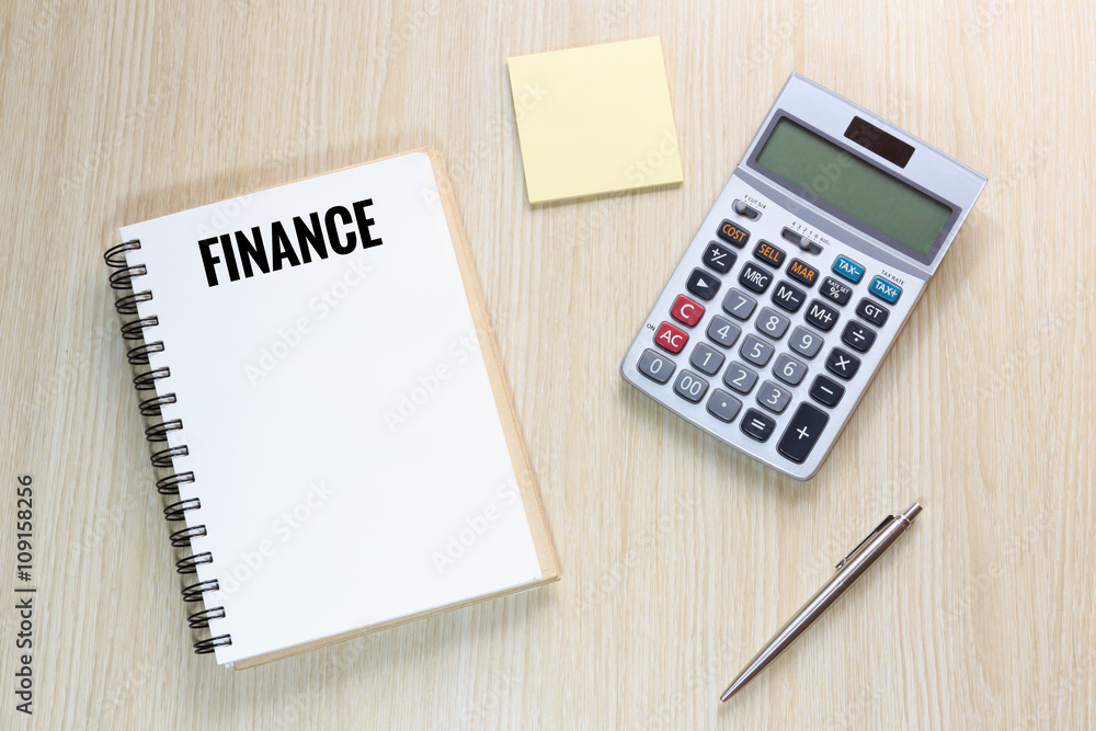 Top view of Finance wording on notebook with calculator, pen Top view of Finance wording on notebook with calculator, pen