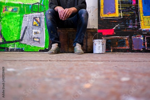 Surface view of male artist sitting between canvases photo