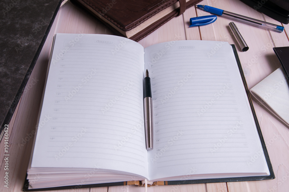 old leather notebook and fountain pen on wooden boards old leather notebook and fountain pen on wooden boards