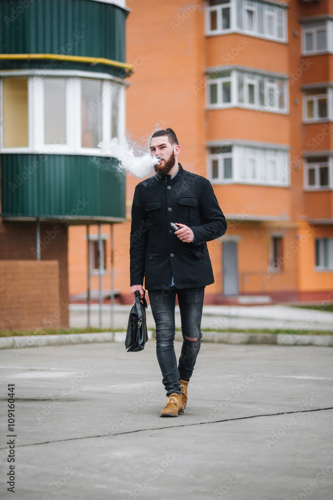 Man with  beard smoking electronic cigarette outdoor