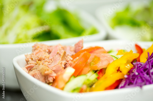 Closeup delicate fresh presentation of tuna salad in white bowl with colourful vegetables such as cole robbie, capsicum, cucumber and tomatoes