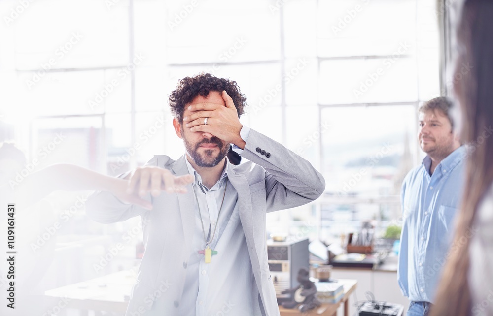 Mature man in team building task, holding hands covering eyes Mature man in team building task, holding hands covering eyes