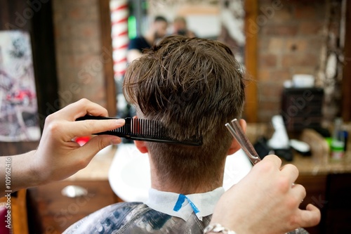 Rear view of young man in barbershop having haircut photo