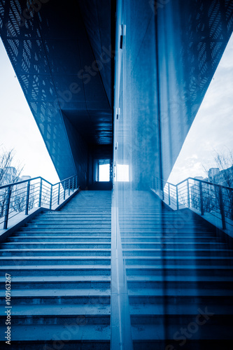staircase reflected in glass wall,blue toned image.