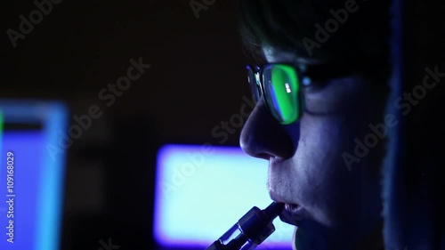 hacker girl works at the computer and smoking electronic cigarette