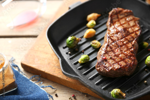 Grilled steak with garlic and Brussels sprouts on grill pan, closeup