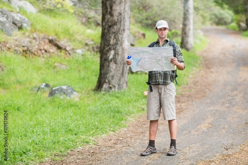 Young man reading map on footpath in forest