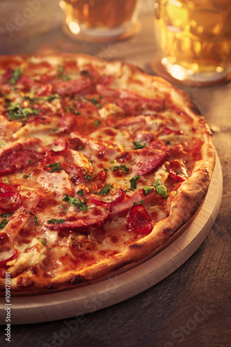 Delicious pizza and glasses of beer are on wooden table, close up