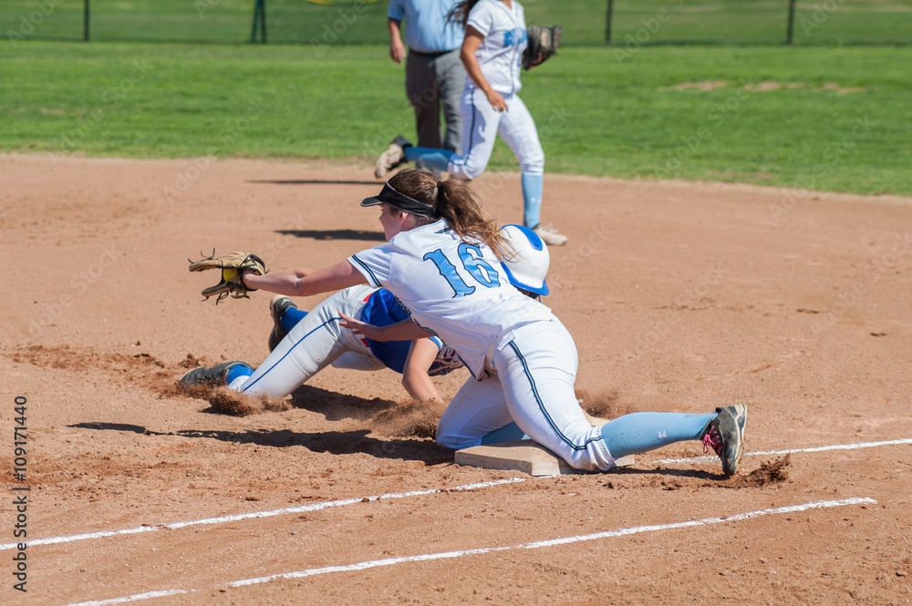 Softball runner and defense player collide at first base. Softball runner and defense player collide at first base.