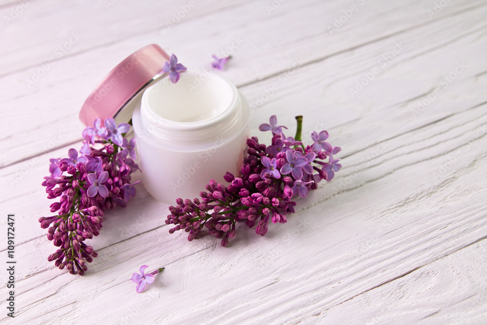 Pot of moisturizing cream with lilac flowers