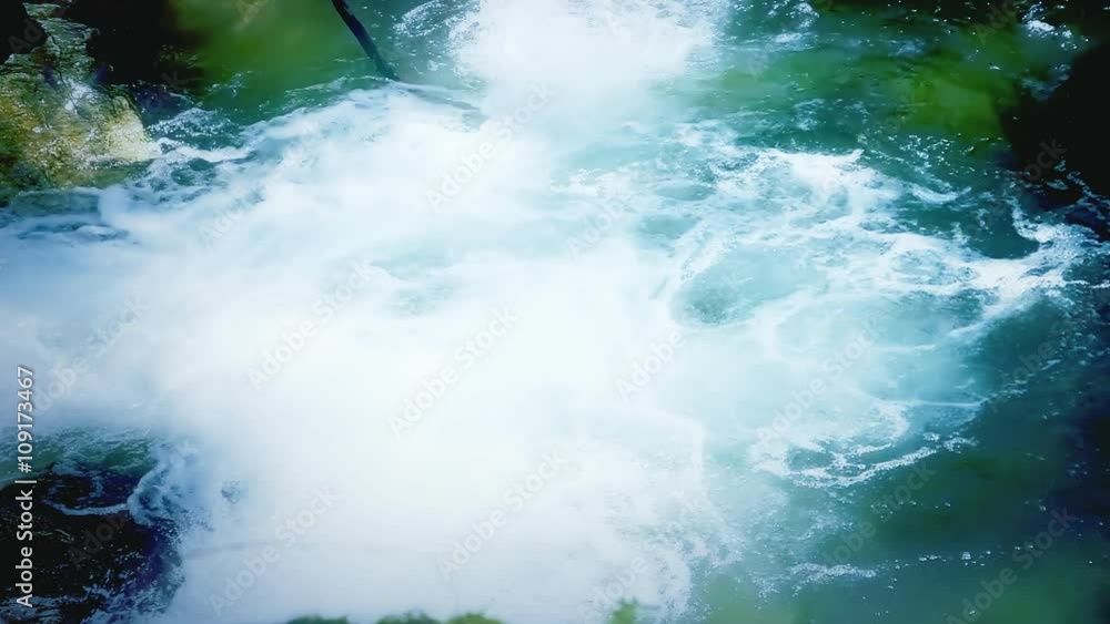 Running water falling into a pond, creating foam and noise. Intense colors, detail shot. Running water falling into a pond, creating foam and noise. Intense colors, detail shot.