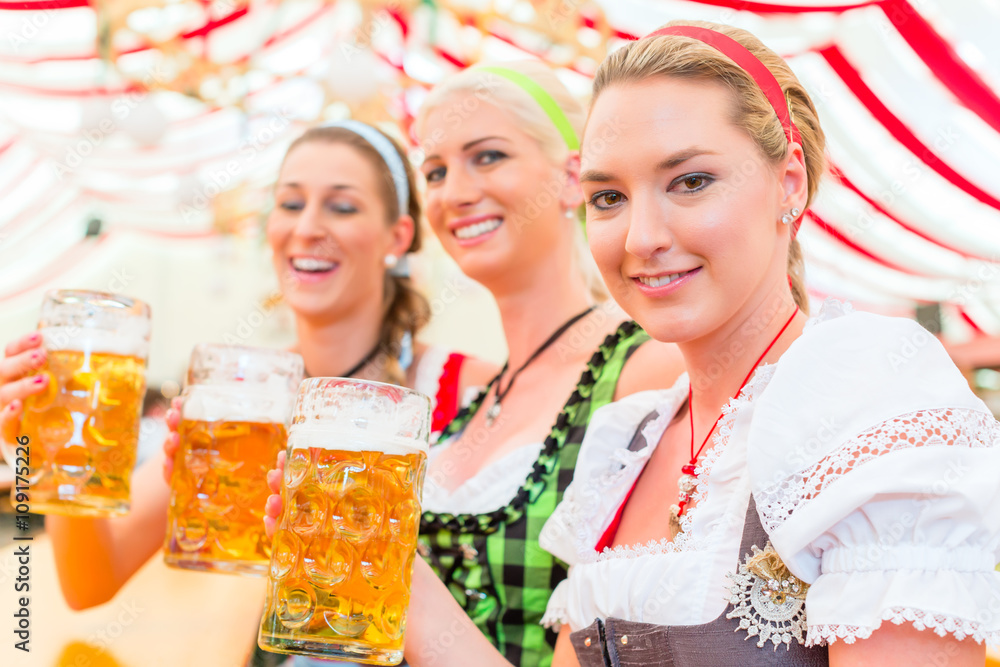 Freundinnen trinken zusammen Bier im Bayrischen Dirndl auf Volksfest Freundinnen trinken zusammen Bier im Bayrischen Dirndl auf Volksfest