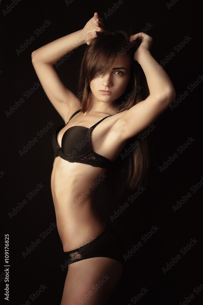 Obraz premium Shot of a sexy woman in black lingerie over black background.