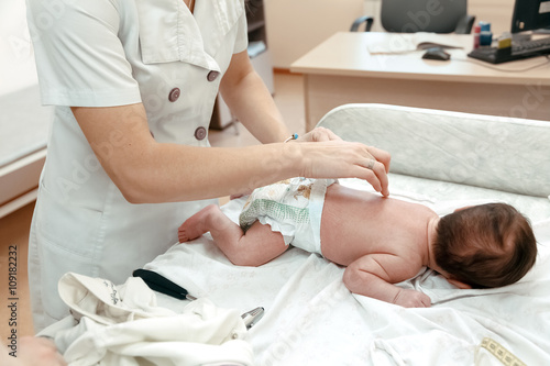 Pediatrician examining littlle newborn baby on the table