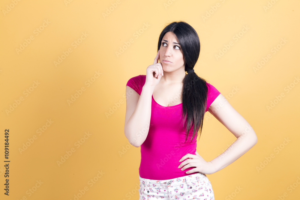 Brunette thinking about something, about taking a decision, over a yellow background. Brunette thinking about something, about taking a decision, over a yellow background.
