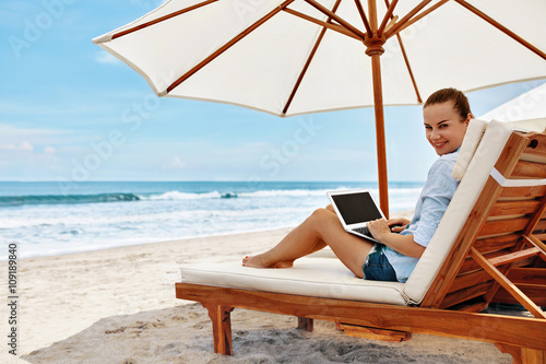 Work At Beach. Successful Business Woman Working Online In Internet Using Laptop Computer Outdoors. Girl Typing On Keyboard While Relaxing By Sea In Summer. Communication Technology Concept © puhhha