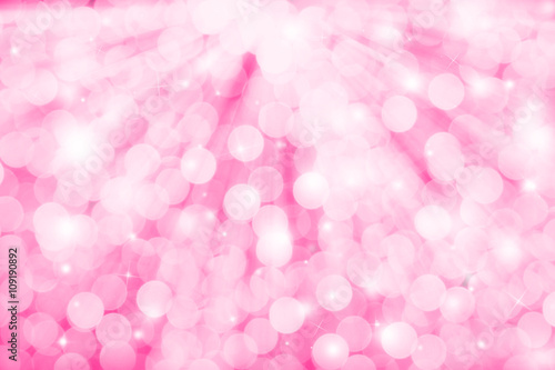 Pink glitter sparkles defocused rays lights bokeh abstract holiday background.