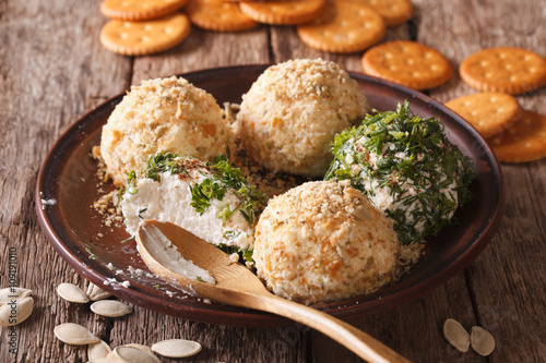 Cottage cheese balls with crackers, herbs and pumpkin seeds close-up. Horizontal
