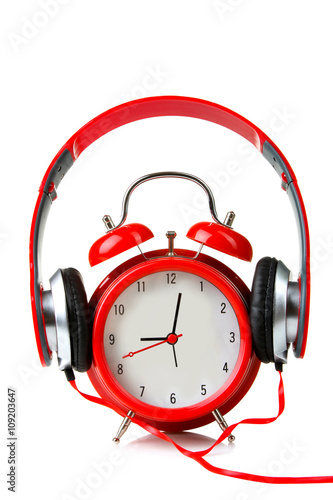 full-size wired headphones dressed on a clockwork alarm clock on white isolated background