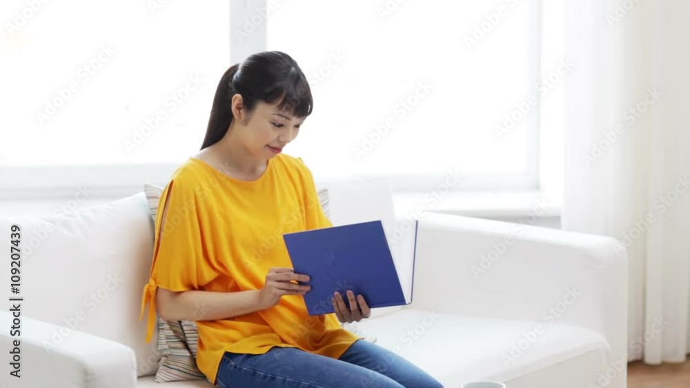 smiling young asian woman reading book at home smiling young asian woman reading book at home