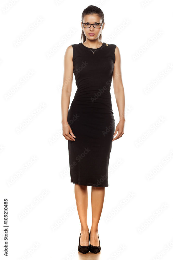 beautiful young woman in a tight black dress posing on a white beautiful young woman in a tight black dress posing on a white