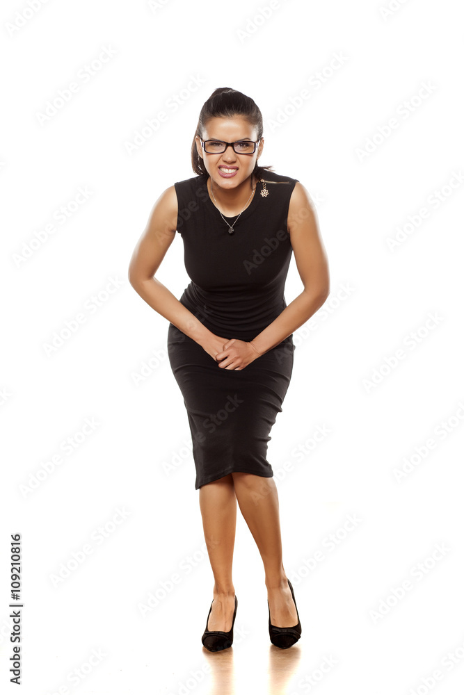 Fototapeta premium beautiful young woman in a tight black dress has a need to urinate