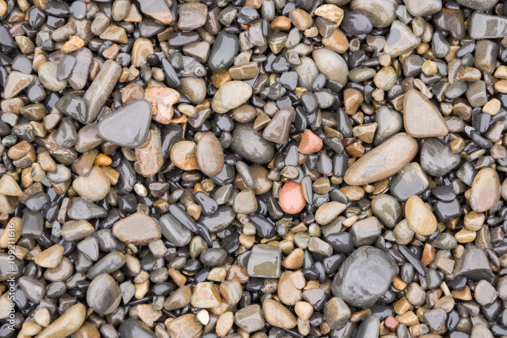 The surface texture of wet sea beach pebbles of medium and small size The surface texture of wet sea beach pebbles of medium and small size