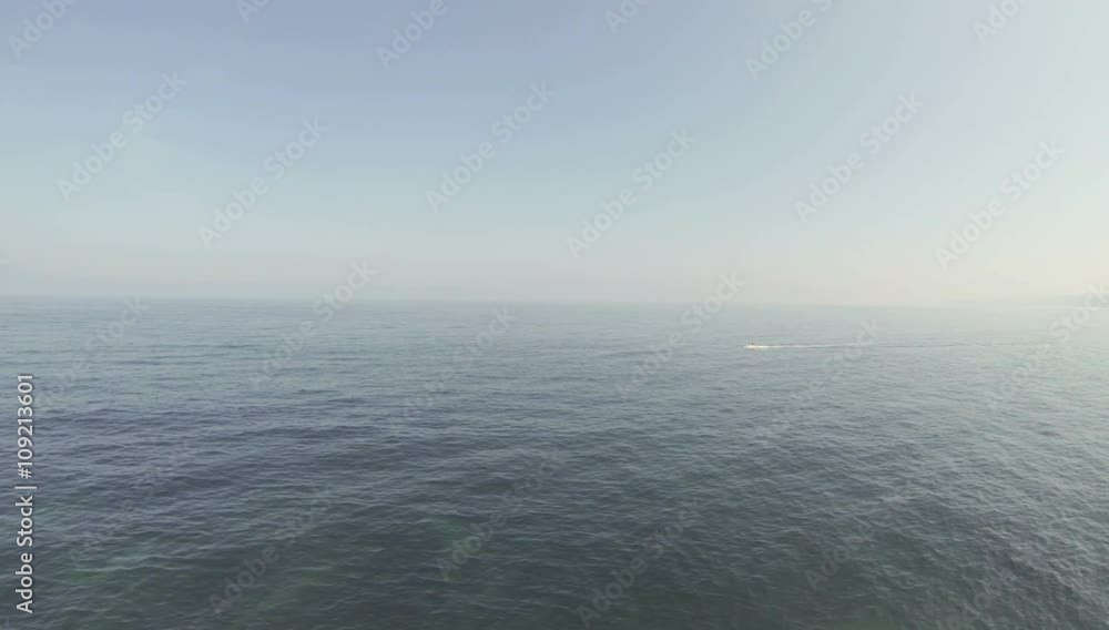 Daytime Ocean horizon with a small boat crossing the scene Daytime Ocean horizon with a small boat crossing the scene