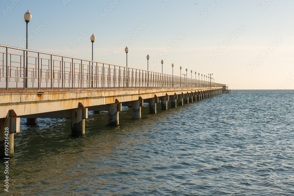 View of the sea pier stretching into the distance at sunset