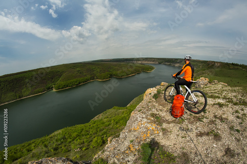 Cyclist in Orange Wear Riding the Bike Down Rocky Hill