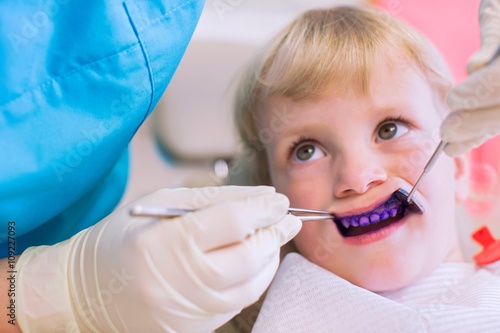 Girl with plaque disclosing tablet on teeth having dental examination