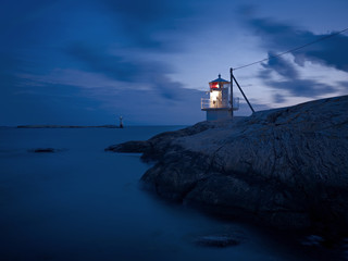Lighthouse on rocky coast at dusk