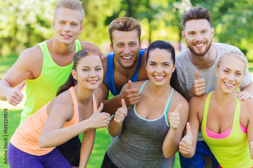 group of happy sporty friends showing thumbs up group of happy sporty friends showing thumbs up