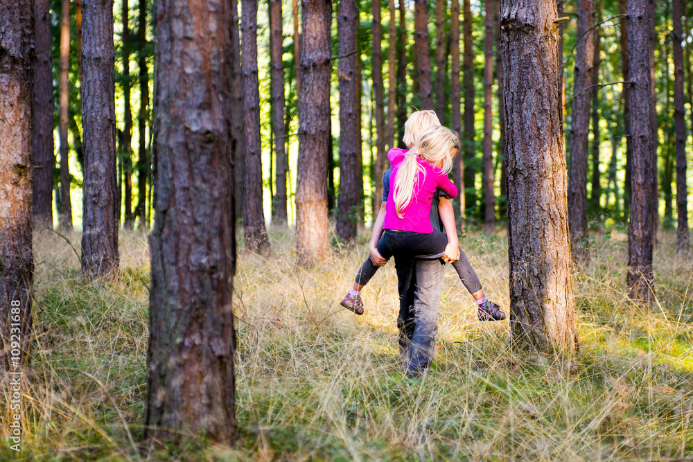Young child boy giving his sister piggyback outdoors in the forest Young child boy giving his sister piggyback outdoors in the forest