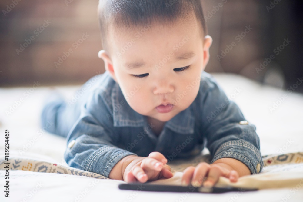 Baby boy playing with smartphone on bed Baby boy playing with smartphone on bed