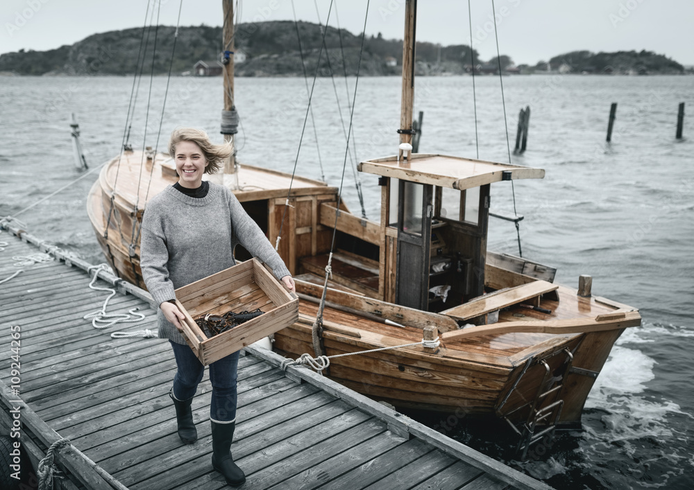Smiling woman carrying lobsters, boat on background Smiling woman carrying lobsters, boat on background