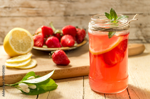 Освежающий, холодный напиток с клубникой, лимоном и мятой на деревянном фоне