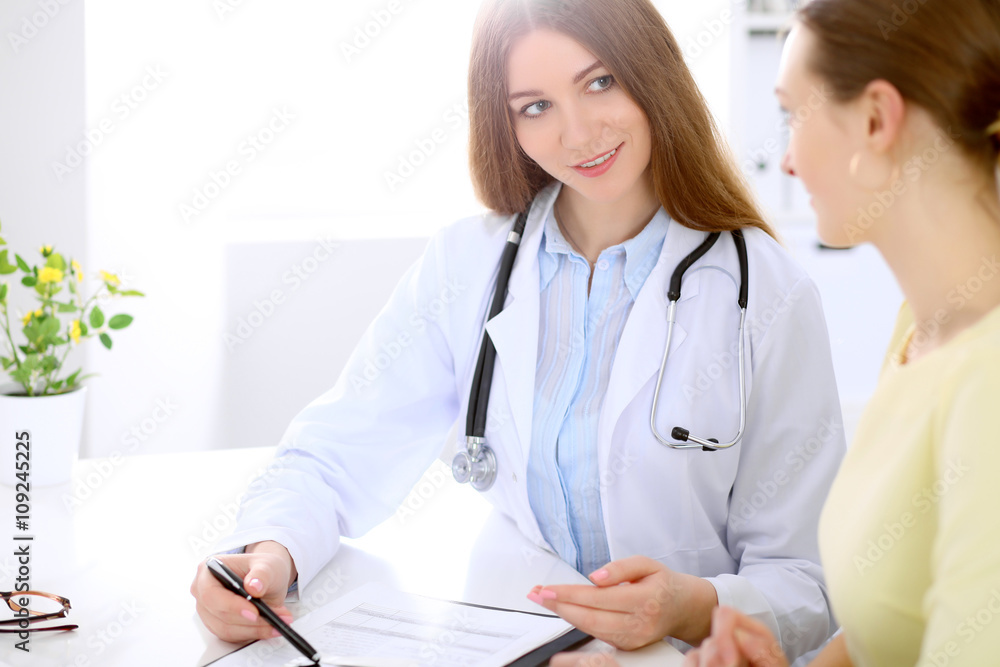Doctor and patient sitting at the desk near window, sun shines Doctor and patient sitting at the desk near window, sun shines