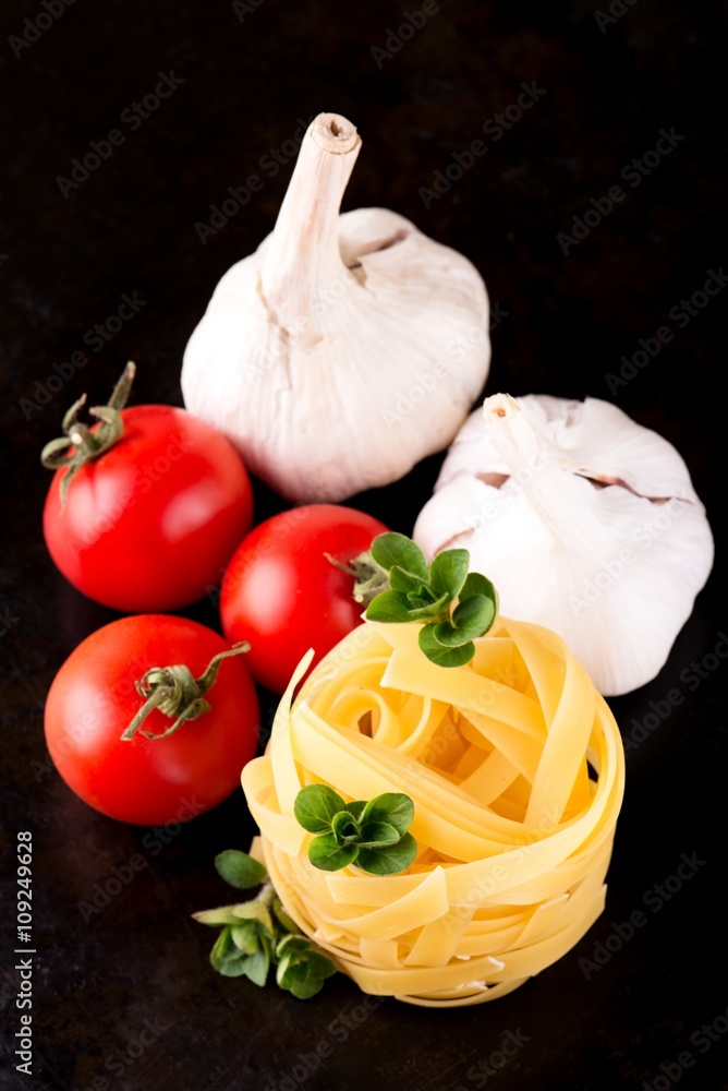 Pasta fettucciny with oregano and vegetable on black plate Pasta fettucciny with oregano and vegetable on black plate