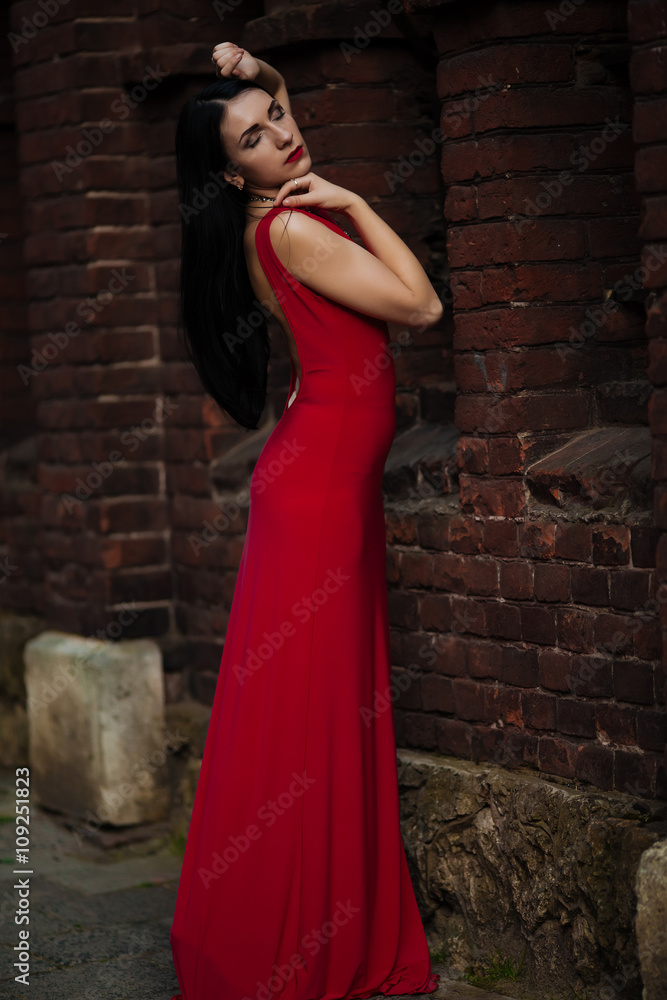 Beautiful young girl posing against a background of red buildings Beautiful young girl posing against a background of red buildings
