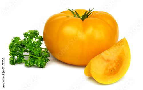 Big fresh yellow tomato and a sprig of parsley isolated on white background.
