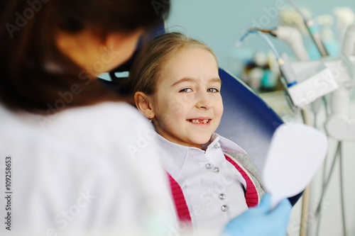 baby girl examines teeth in a dental mirror