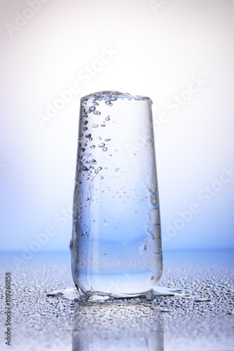 Full drinking glass with reflection in drops of water