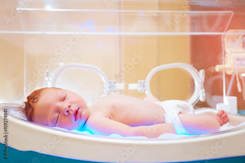 newborn baby get the light therapy in infant incubator photo