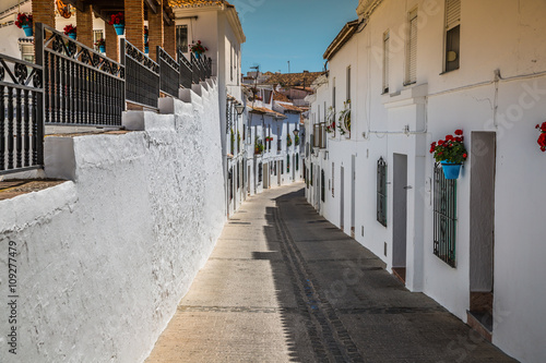 Picturesque street of Mijas with flower pots in facades. Andalus