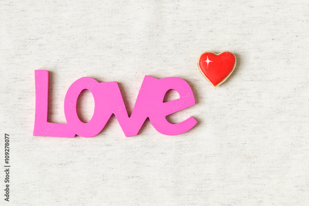 Love word and heart shaped cookie on linen background Love word and heart shaped cookie on linen background