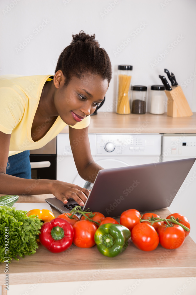 Woman Using Laptop In Kitchen Woman Using Laptop In Kitchen